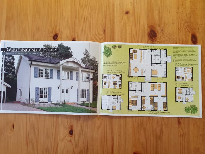 Öppen katalog som visar ett vitt tvåvåningshus med planlösningar för varje våning bredvid.