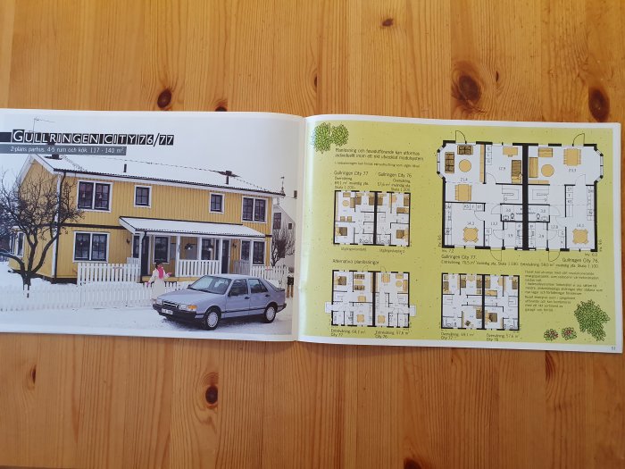En öppen katalog visar ett gult hus på vänster sida och husets planlösningar på höger sida.