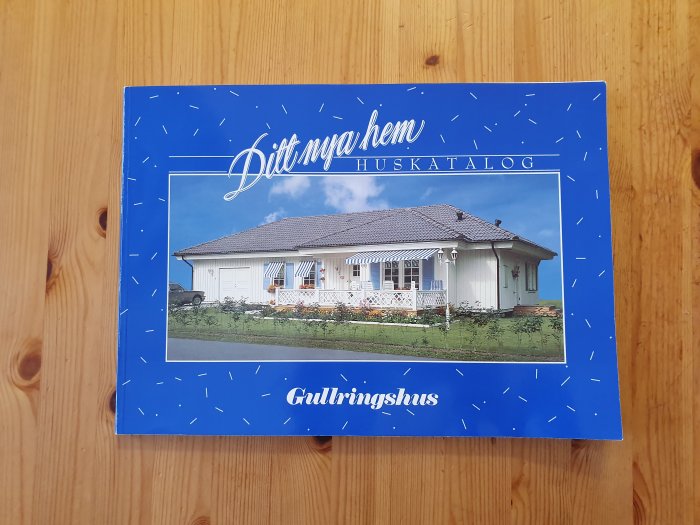 Framsida på en huskatalog med bild av ett vitt enfamiljshus och texten "Ditt nya hem - Huskatalog Gullringshus".