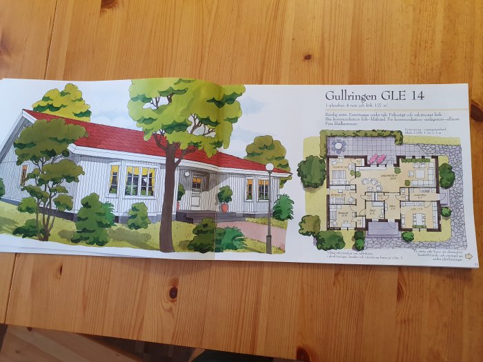Illustration av enplanshuset 'Gullringen GLE 14' med fasadvy och detaljerad planlösning öppen i en katalog på ett träbord.