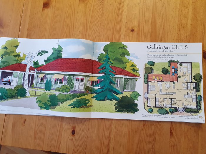 Illustration av husmodellen 'Gullringen GLE 8' i en katalog öppnad på trädgårdsbord.