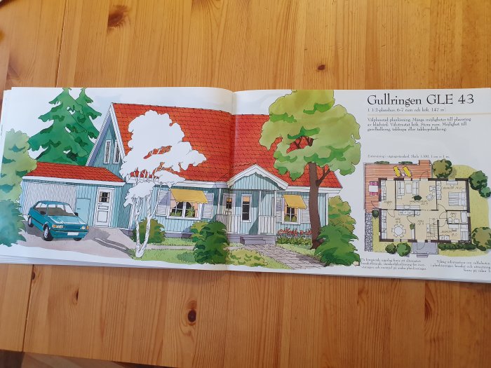 Illustration av ett rött hus med planlösning och beskrivning ur katalog, sida öppnad på ett träbord.
