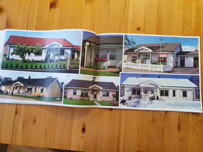 En öppen katalog som visar olika husmodeller, från vänster till höger, på en uppslagen träyta.