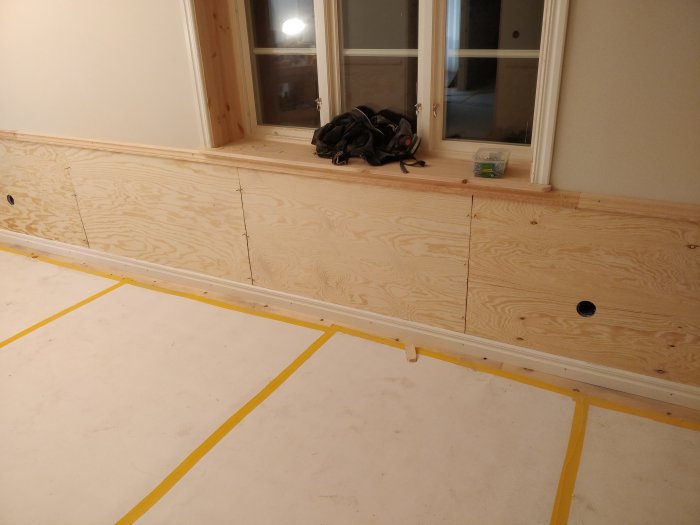 Nyinstallerat obehandlat trägolv och bröstpanel av furuplywood i ett renoveringsprojekt.