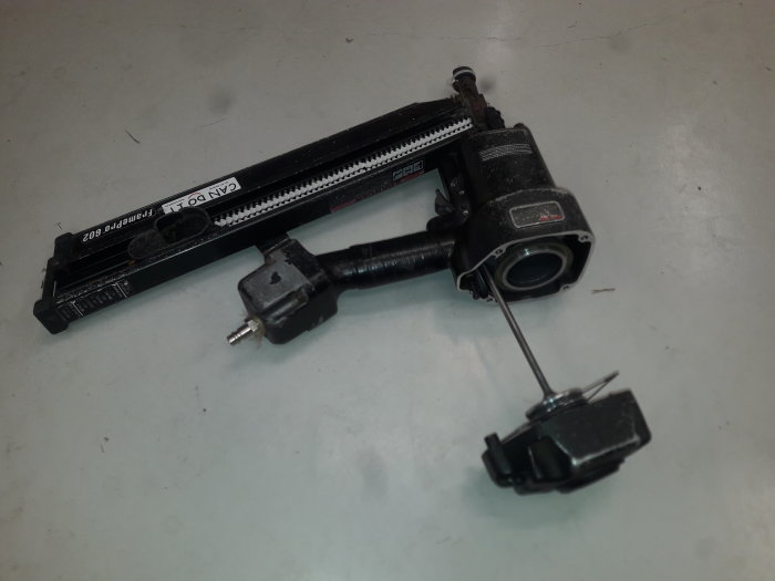 En isärplockad Senco stompistol modell 602 på en arbetsbänk som visar dess olika komponenter.