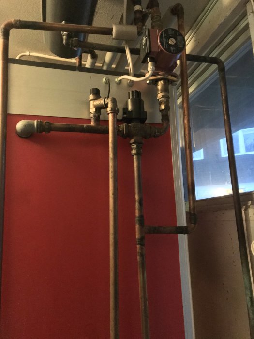 Värmesystem med rör, ventiler och en cirkulationspump i ett pannrum.