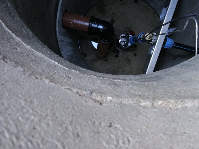 Inloppsrör och pumputrustning i en grå betong trekammarbrunn.