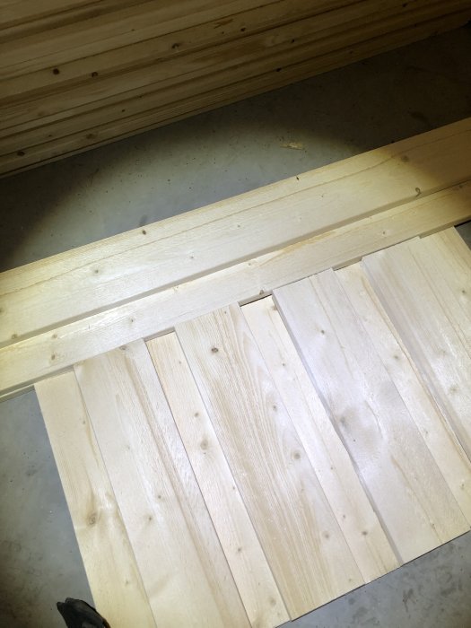 Översikt av stående lockpanel i trä med en horisontell bräda som möjlig midja på ett betonggolv.