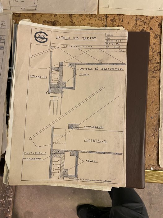 Fotografi av en arkitektritning med detaljer vid takfot för ett Gullringhus, visas på en bordsskiva.