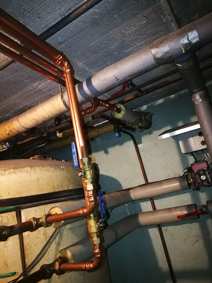 Rörsystem och element i källare med koppar- och isolerade rör samt en cirkulationspump.
