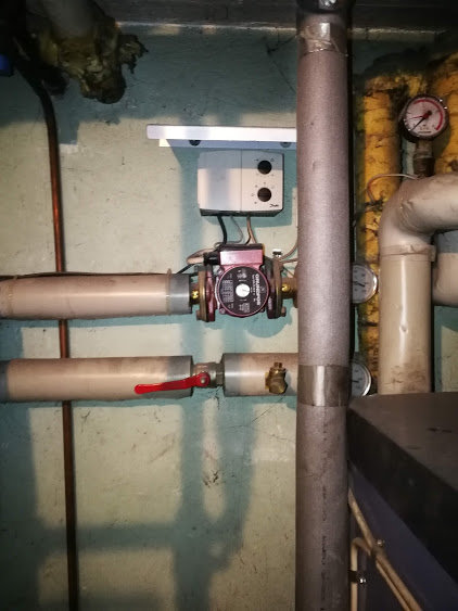 Värmesystem med rör, cirkulationspump och manometer visande lågt tryck.