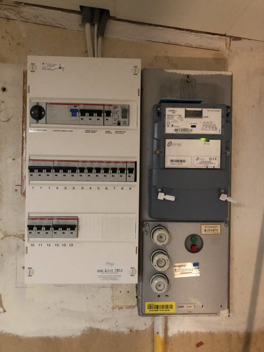 Överblick av ett elskåp med säkringsbrytare och en elektricitetsmätare på en vägg, märkt "20A" men ska vara 16A.