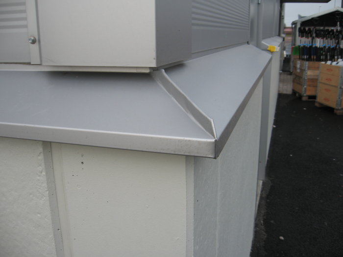 Hörn på en byggnad med prydligt monterad plåt utan vassa kanter.