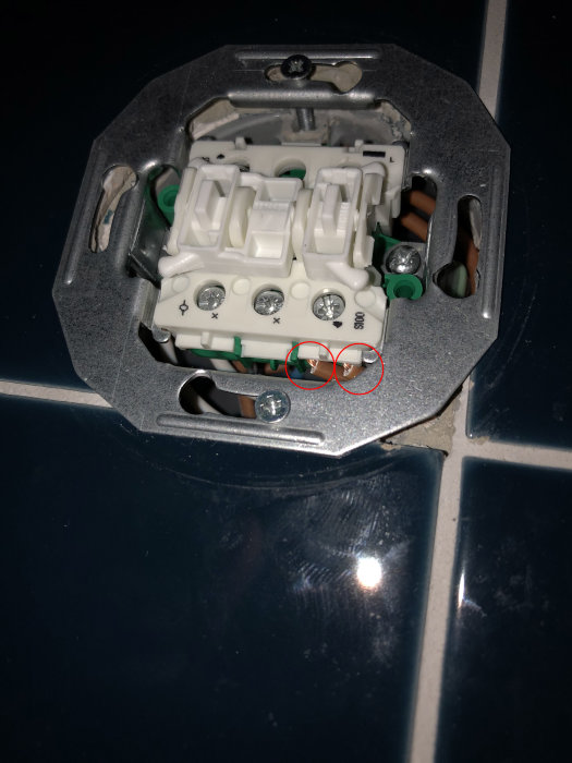 Öppen strömbrytare med markerade kablar, en svart kabel synlig i övre högra hållet.