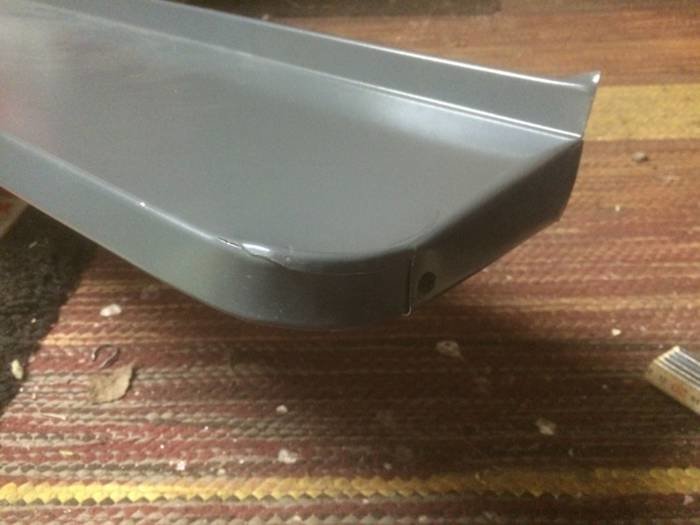 Närbild av ett metallhörn med en elegant rundad kant placerad på ett mönstrat underlag.