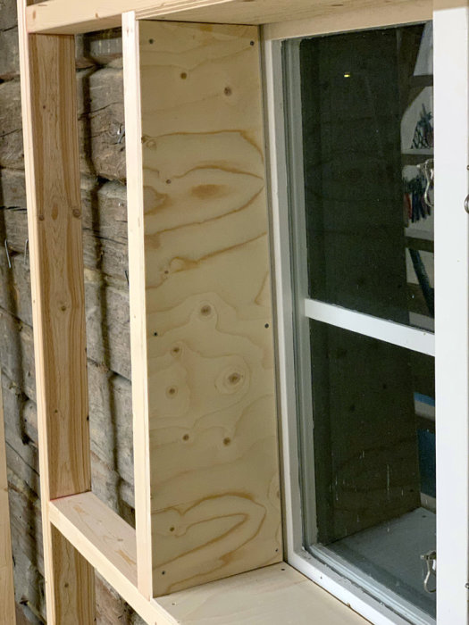 Förreglad vägg för isolering med synlig avvikelse vid fönsterkant i ett garagebygge.