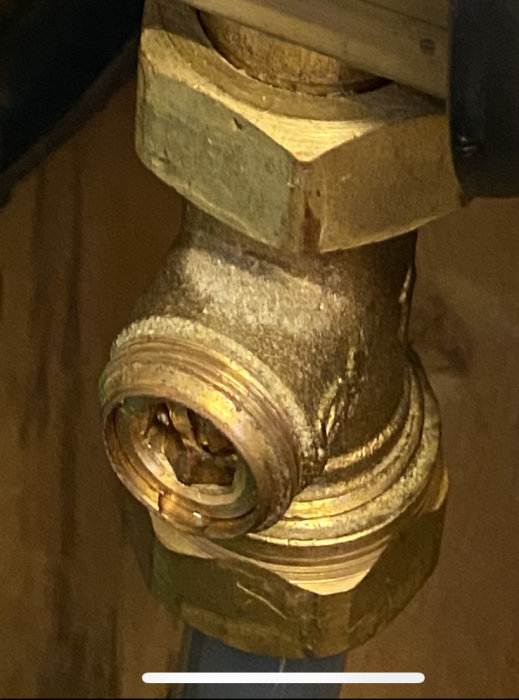 Närbild på en öppnad golvvärmereturventil med synliga skruvar och smutsavlagringar som justerats för värmejustering.