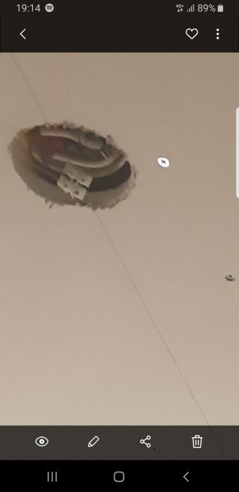 Öppning i ett vitmålat tak med en elektrisk takdosa som sitter en bit ovanför det nygipsade taket.