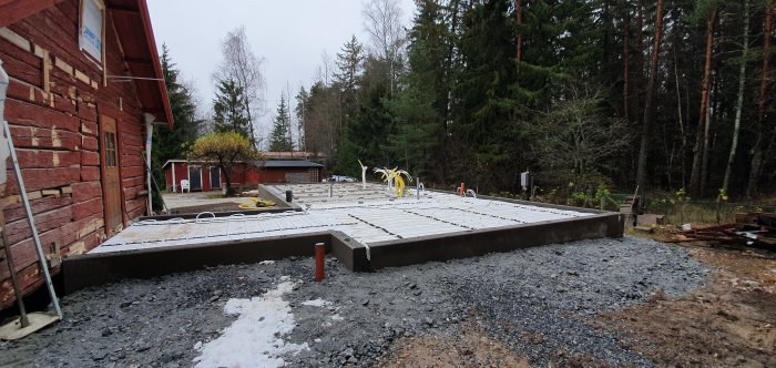 Nybyggd husgrund med isolering, golvvärmeslingor och armering, redo för betonggjutning.