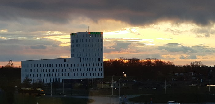 Solnedgång över modern byggnad i Hyllie, Malmö med dramatisk molnhimmel.