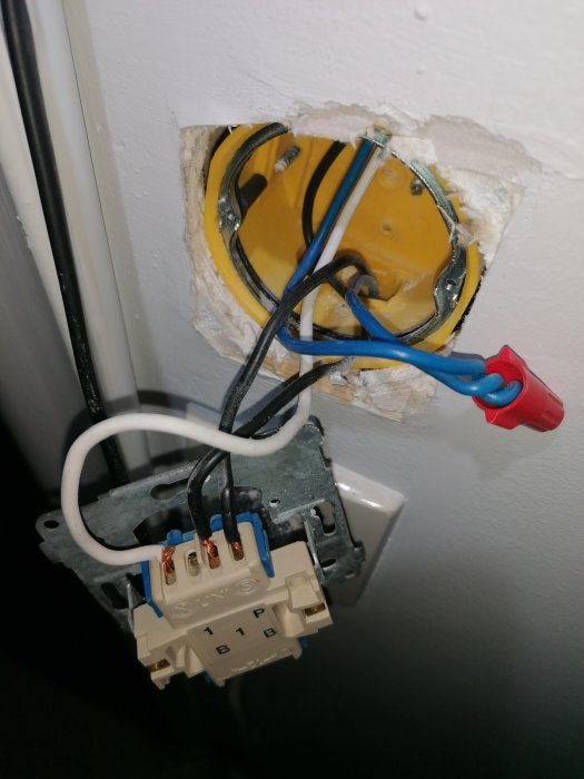 Öppet eluttag med exponerade kablar och ansluten Nexa ZV-9101 strömbrytare under installation.