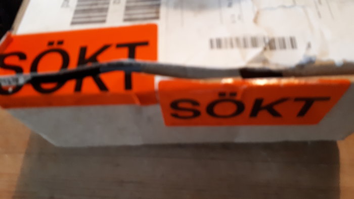 Paket med orange lapp märkt "SÖKT", symboliserande en missad paketleverans.