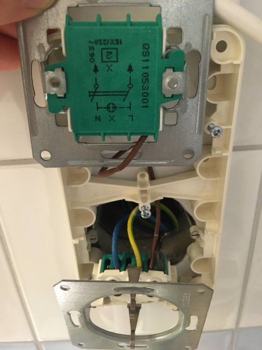 Öppet eluttag och brytare med synliga ledare i badrum, brun ledare är inkopplad.