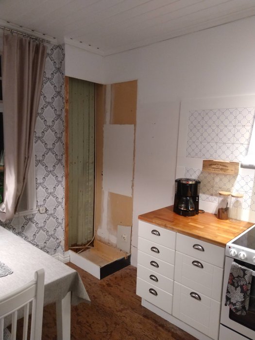 Kökshörn under renovering med borttaget högskåp och tillfälligt återanvänt bänkskiva ovanpå nya skåp.