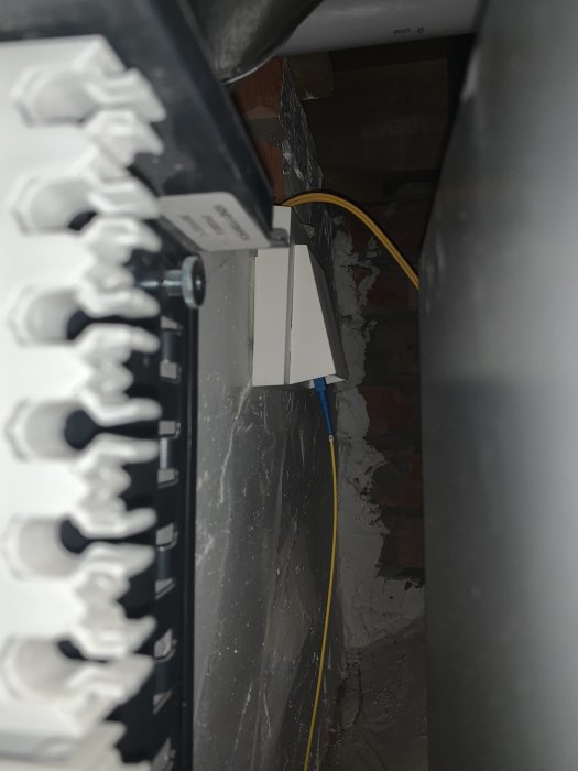 Patchpanel och bredbandsdelare anslutna med fiberpatchkabel i ett tekniskt utrymme.