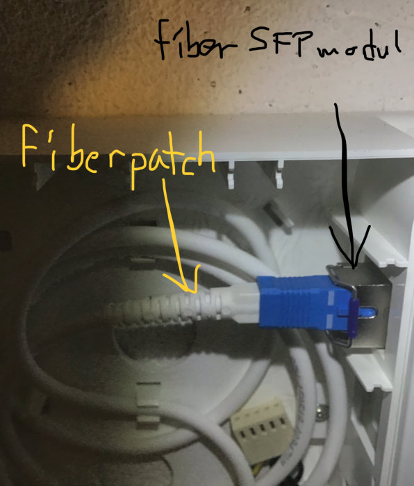 Inteno tjänstefördelare öppen med synlig fiber SFP-modul och fiberpatch ansluten, samt markerad grå kabel.