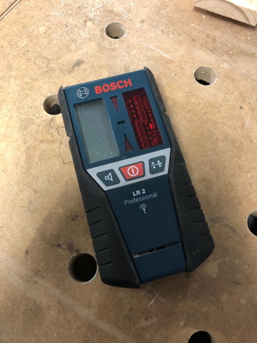 Bosch LR2 Professional laser mottagare, begagnad, placerad på ett träbord med borrade hål.