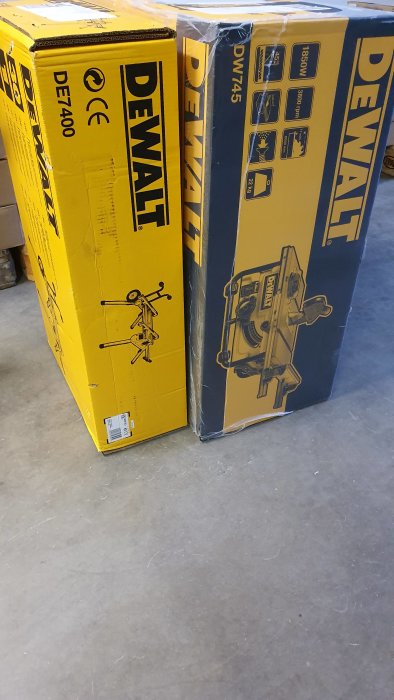 Två obrutna kartongförpackningar med DeWALT varumärkesverktyg på ett betonggolv.