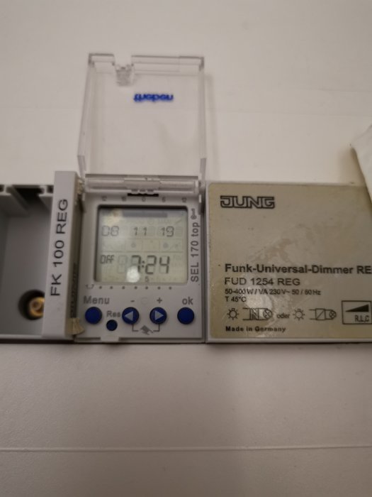 Elektronisk timer och dimmer med digital display och knappar monterade på en vit vägg.