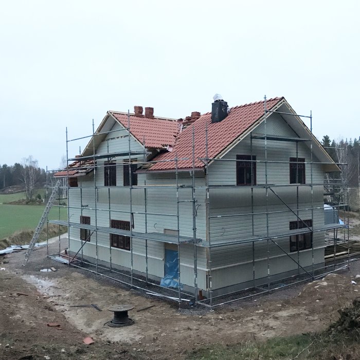 Ett hus under renovering med nästan färdiglagt tegeltak och ställningar runt fasaden.