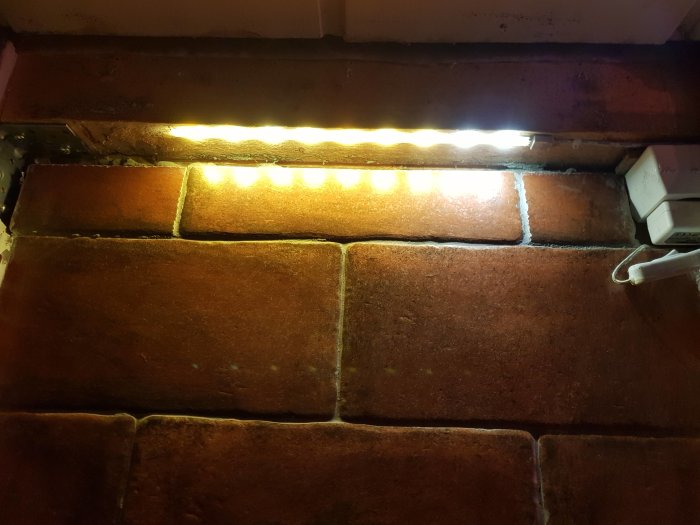 Dekorstenar på en vägg upplysta av en LED-list med ojämn färg, där två dioder till höger fortfarande är vita.