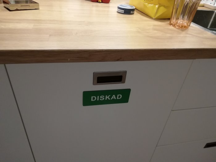 En vitlackerad diskmaskinslucka med en grön skylt som säger "DISKAD" monterad med neodymmagneter.