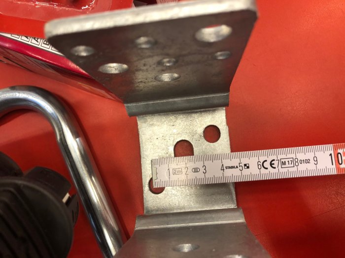 Närbild på en stolpskos mått med en metersticka som visar bredden i millimeter, med fokus på hålavstånd.