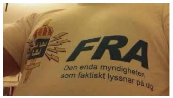 T-tröja med text "FRA Den enda myndigheten som faktiskt lyssnar på dig" med illustration av en krona och blixtrar.