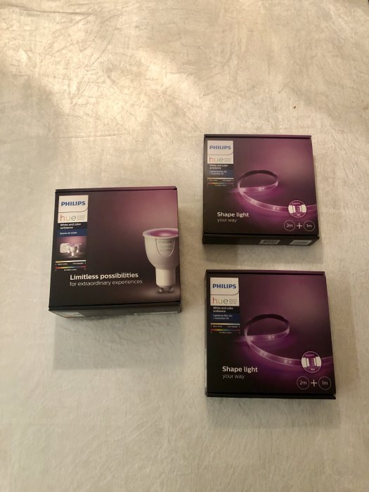 Tre lådor med Philips Hue smart belysningsprodukter på en texturerad yta.