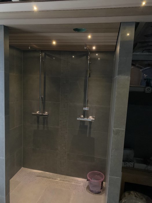 Modern dusch med glasväggar, två regnduschhuvuden och inbyggd belysning.
