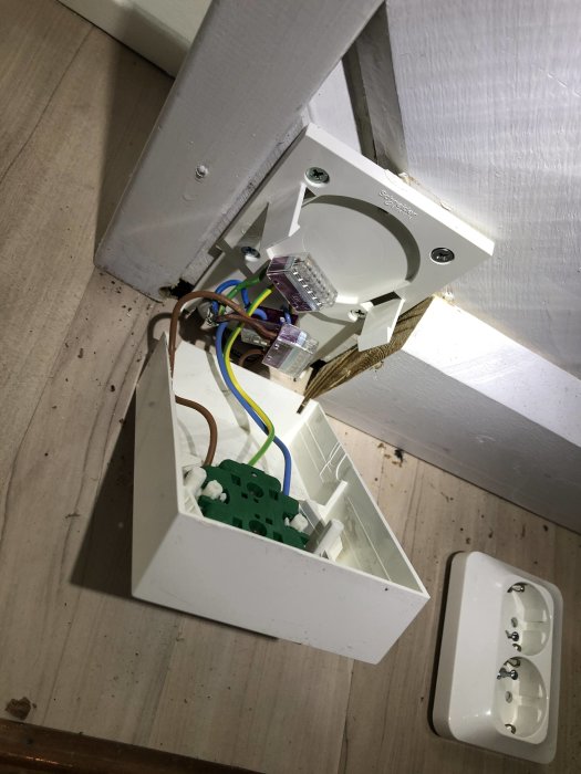 Öppen elektrisk kopplingsdosa med lösa kablar vid takfäste.