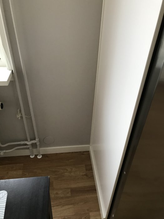 Hörn i renoverat kök med elrör och täcklock där vägguttag varit, fönsterram till höger.