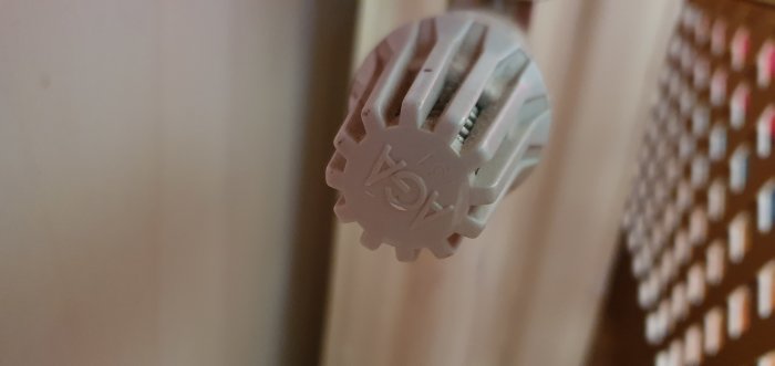 Radiator termostatknopp i närbild, potentiellt i behov av justering eller reparation för bättre värme i vardagsrum.