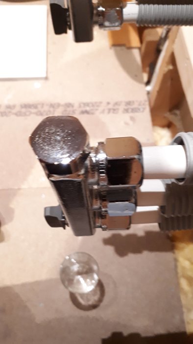 Vattetätplastkoppling med en droppe vatten som läcker ut på golvet.