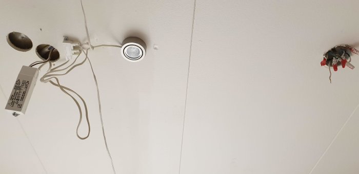 Oorganiserad installation av lampkablage i tak, blottade ledningar och driver för belysning, felaktig färgkodning.