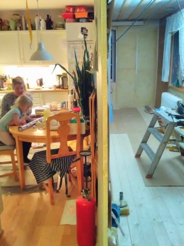 Renovering i hemmet med gipsvägg som delar befintligt rum och påbyggnad, personer syns i förgrunden.