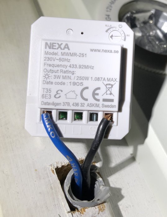 NEXA mottagare MWMR-251 monterad på vägg med blå och svart kabel ansluten, vit knapp synlig.