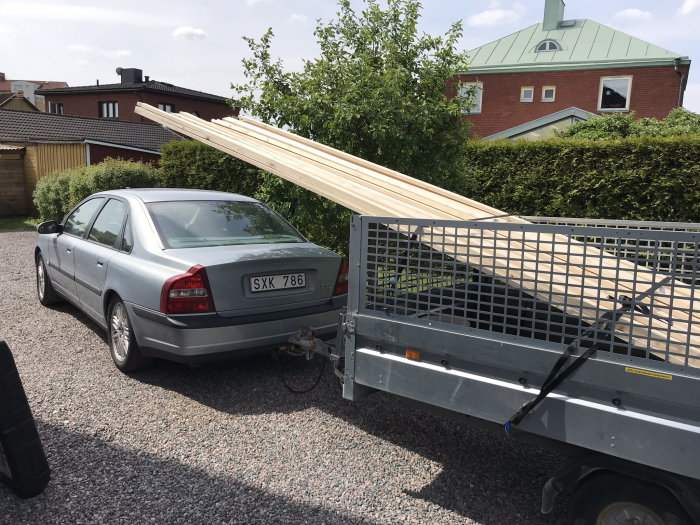 Bil och släpvagn lastade med glespanel brädor redo för byggprojekt