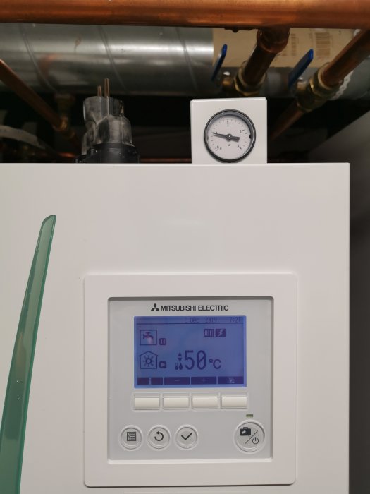 Värmesystemets kontrollpanel visar 50 grader, termostat och rör i bakgrunden.