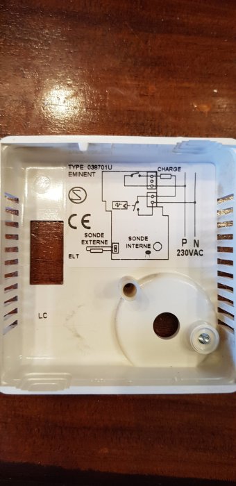 Bild av en gammal golvvärmetermostatets insida med elektrisk kretsschema och anslutningsmärkningar för installation.